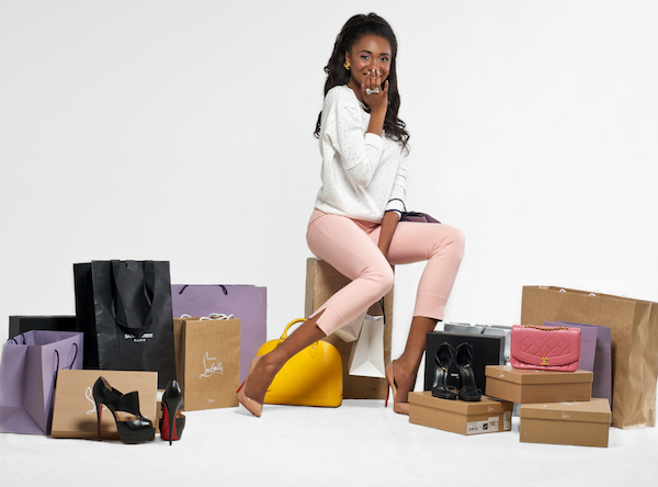 African-American stylist Stephanie Alexis sits atop a pile of luggage dreesed in heels and tight pink jeans.